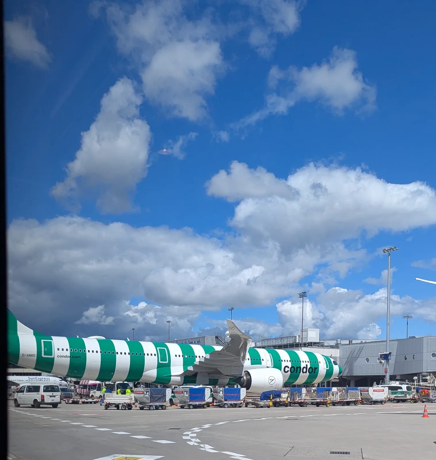 Зелёно-белый самолёт Condor под облаками у терминала